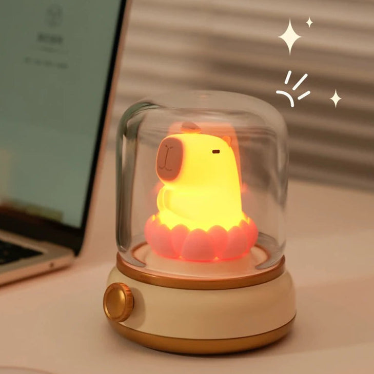 Decorative lamp with kawaii capybara candlelight mode on a desk next to a laptop