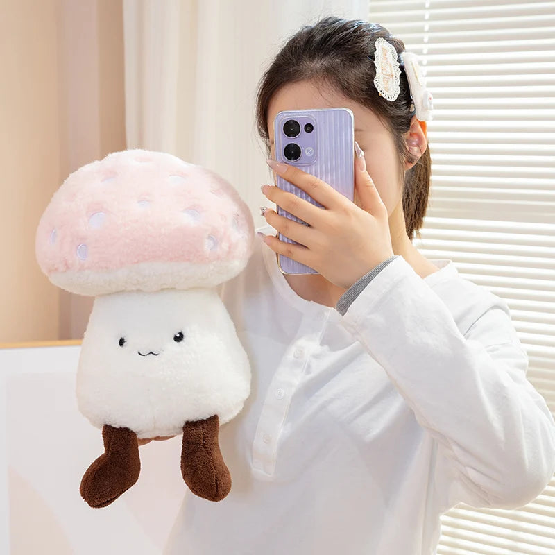 Person holding a kawaii plush mushroom toy and a phone with a light-colored background