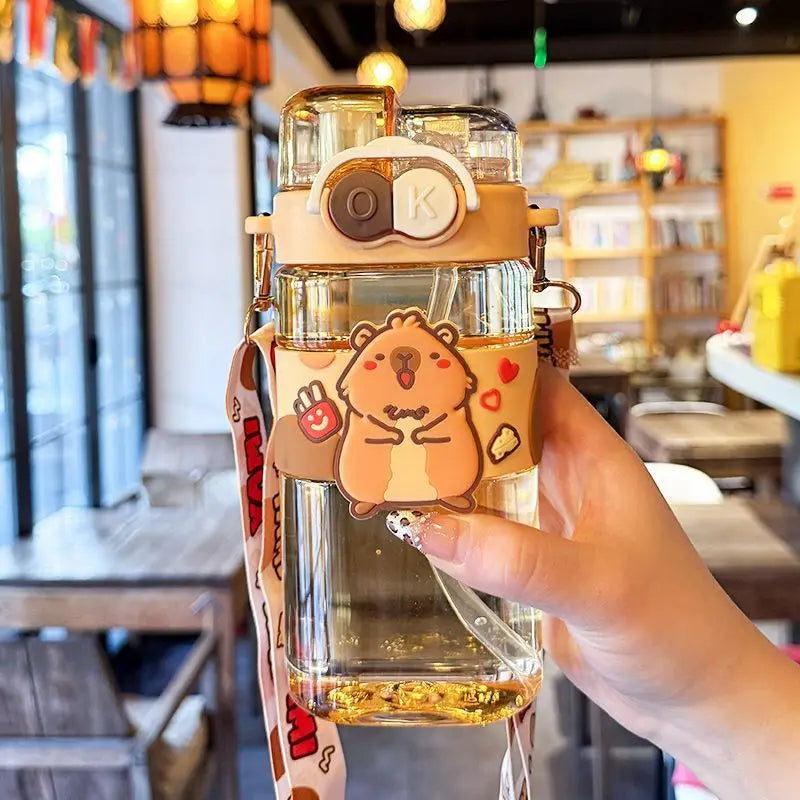 Clear kawaii water bottle with cartoon hamster design held in a hand, indoor setting