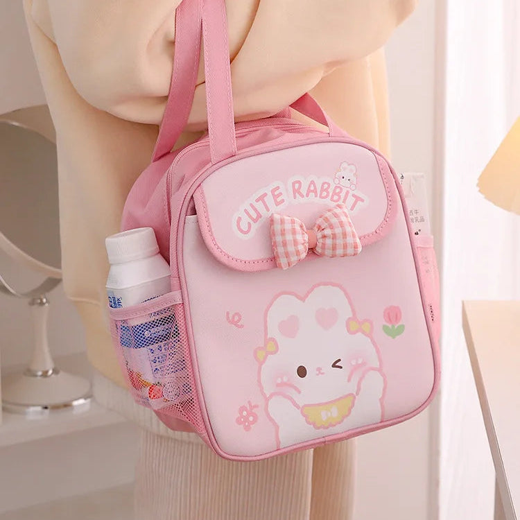 Pink kawaii lunch bag with a cute rabbit design held by a person.