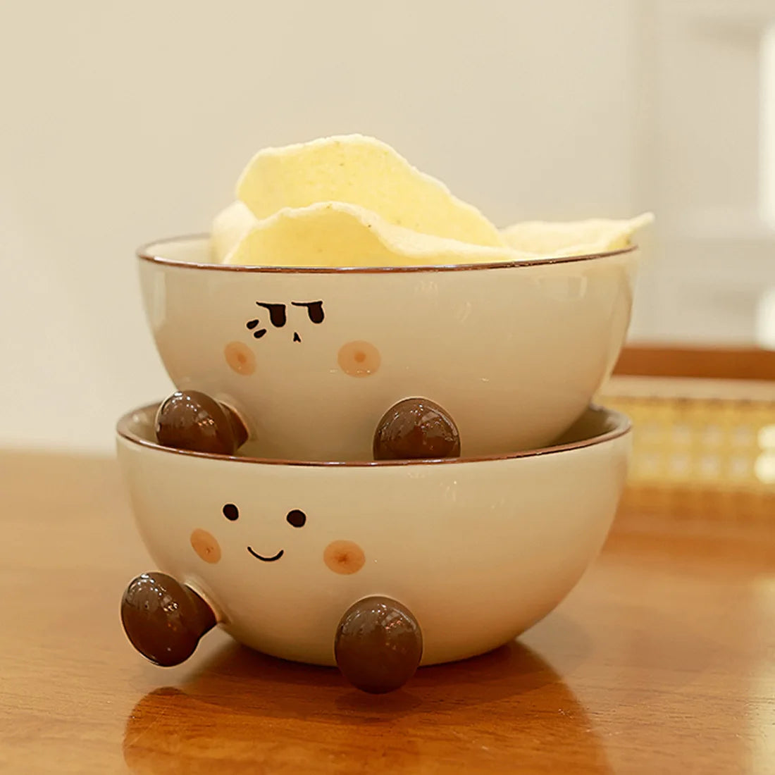 Two stacked ceramic kawaii ramen bowls with cartoon faces on a wooden surface