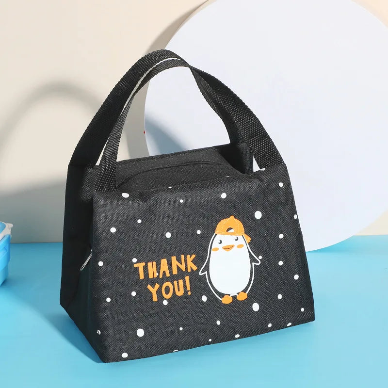 Black polka dot kawaii lunch bag with a penguin design and 'THANK YOU!' text on a blue surface.