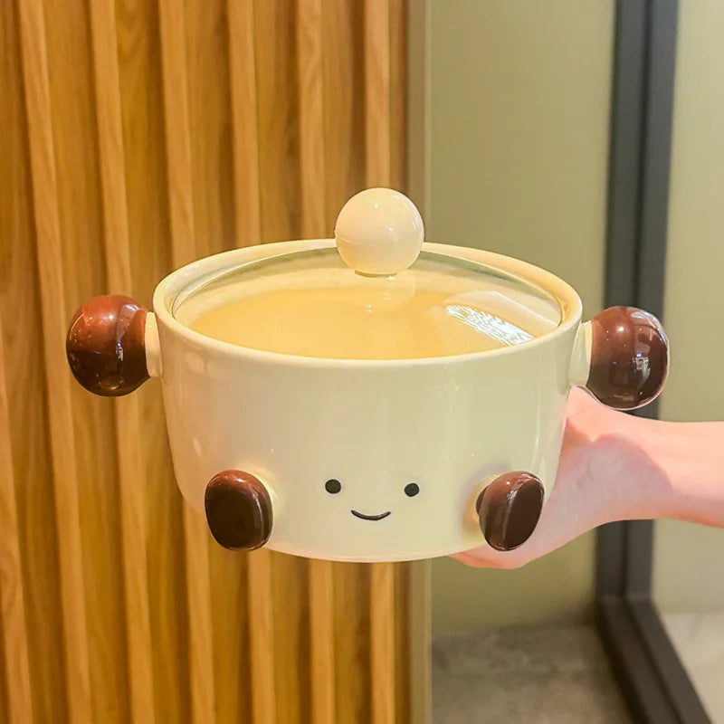 Ceramic kawaii bowl with a smiley face design held by a hand against a wooden background