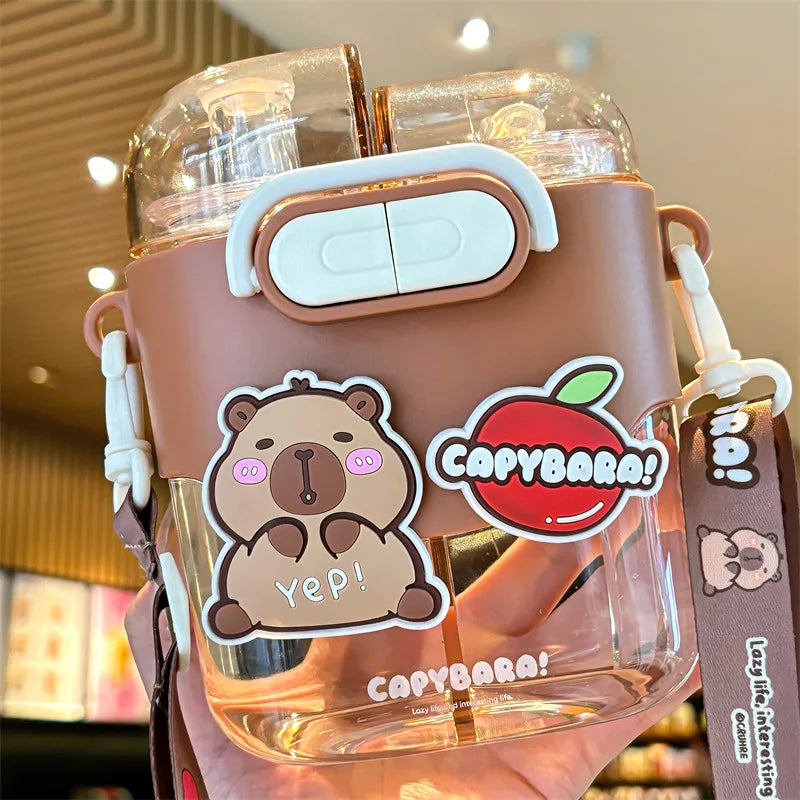 Capybara-themed kawaii tumbler with stickers and a strap in a blurred indoor setting