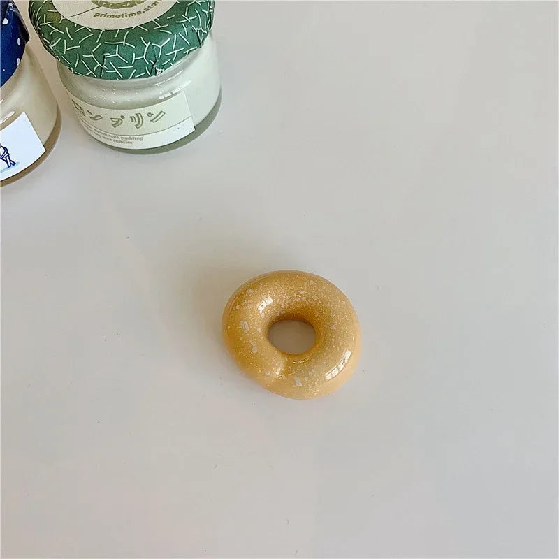 Small donut shaped kawaii chopstick holder on a light gray surface with jars in the background