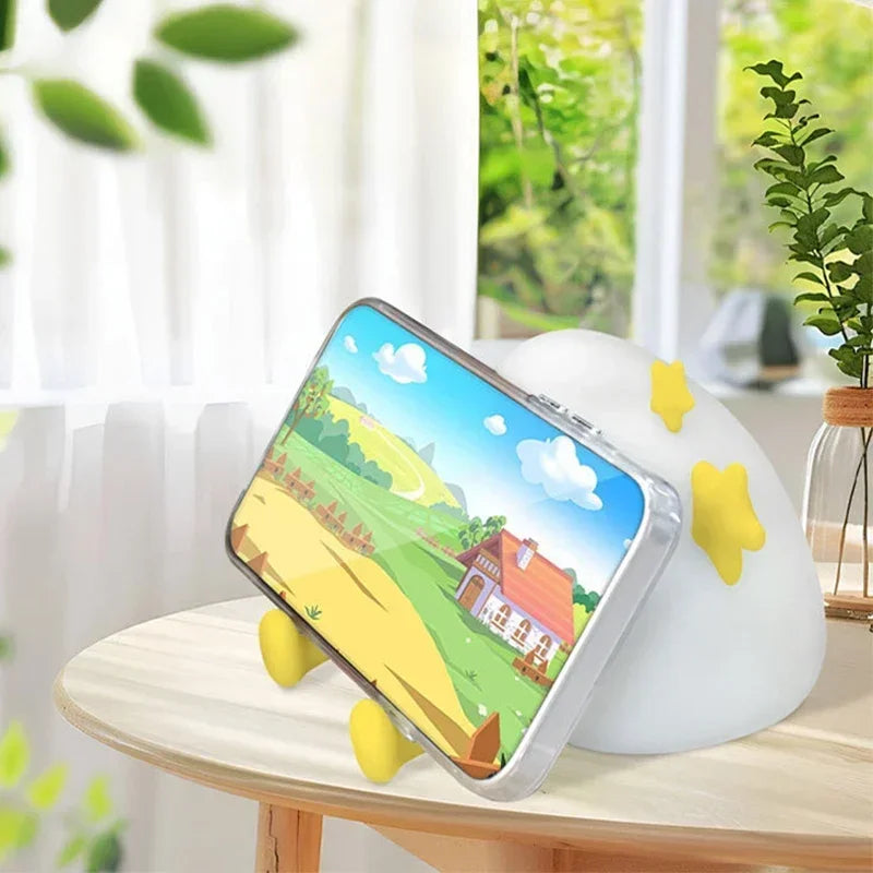 Kawaii phone holder with cartoon landscape design on a table with a blurred indoor background