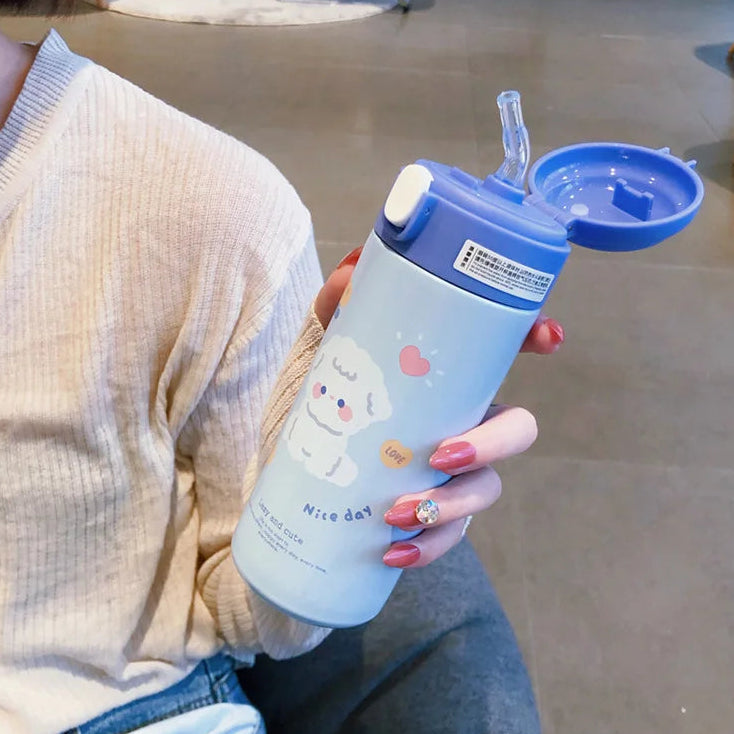 Person holding a blue and white kawaii tumbler with a cartoon design.