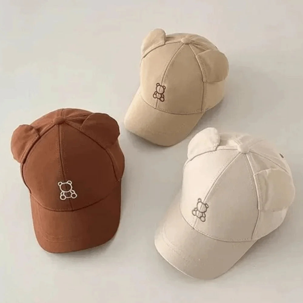 Three Kawaii baseball caps in brown, beige, and light beige on a light background