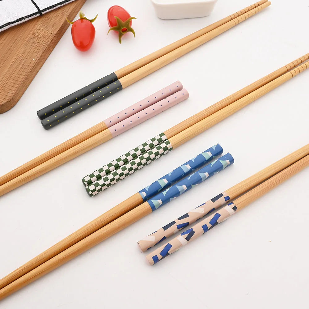 Set of wooden kawaii chopsticks with colorful patterned covers on a white surface.