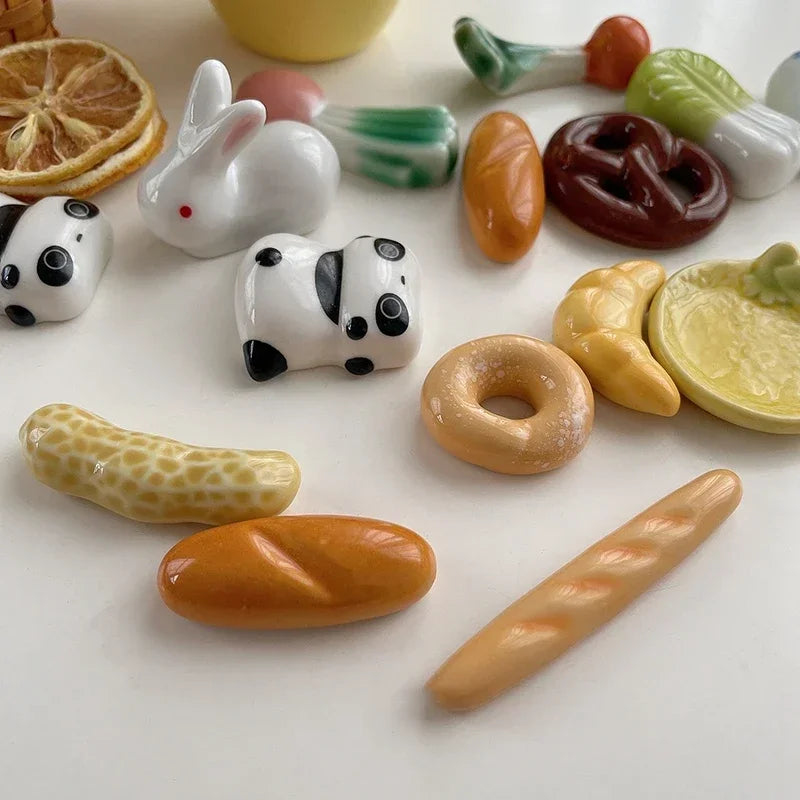 Collection of miniature ceramic food kawaii chopstick holders on a white surface