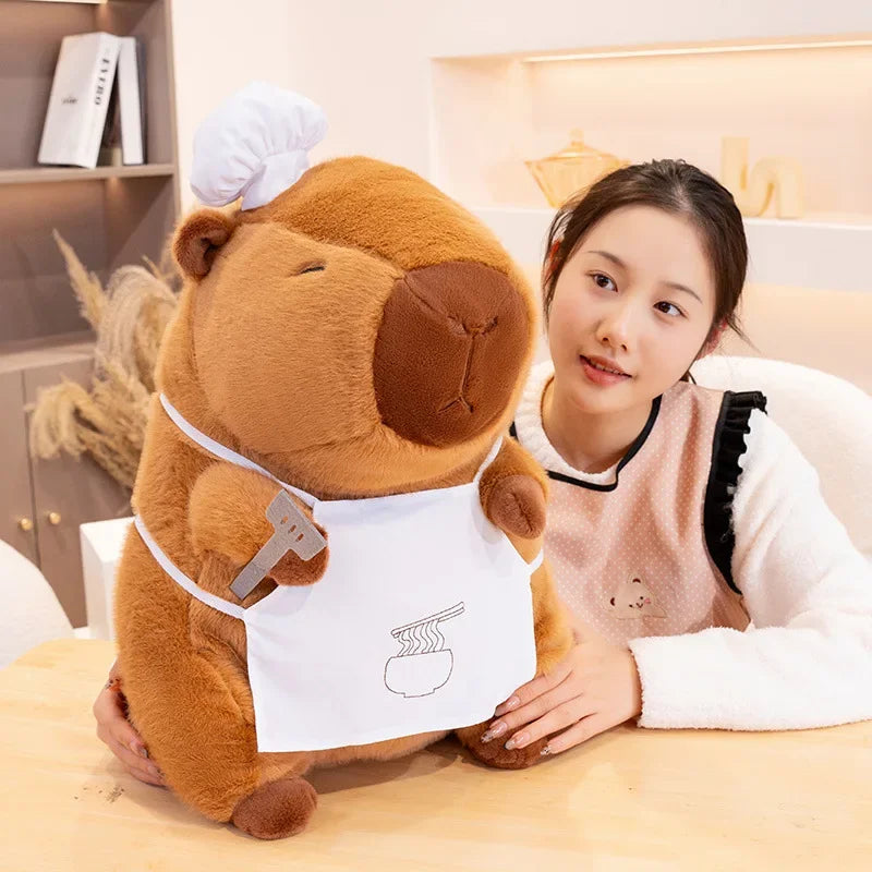 Person sitting next to a large kawaii plush dog toy with an apron in a cozy room.