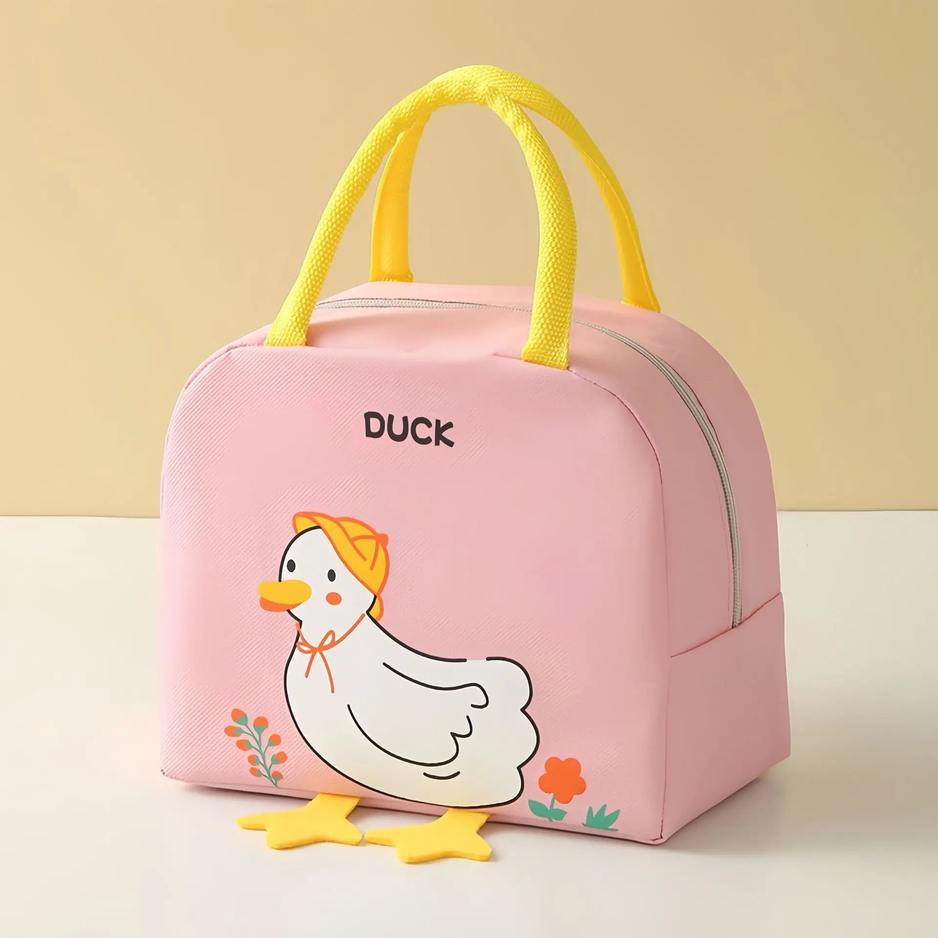 Pink kawaii lunch bag with duck design and yellow handles on a beige background