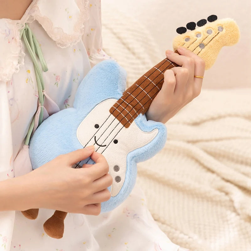 Child holding a kawaii plush toy guitar with a smiling face on a soft surface