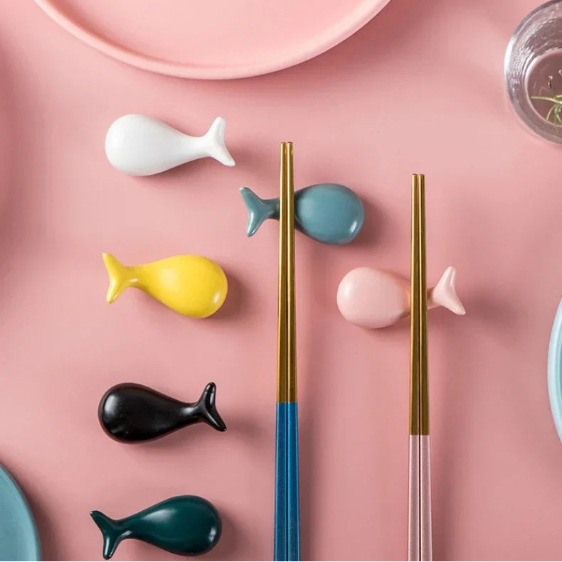 Colorful ceramic kawaii chopstick rest with fish designs on a pink surface