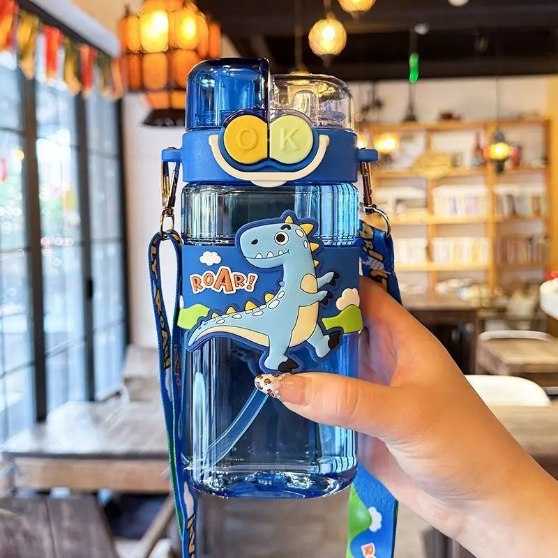 Blue kawaii water bottle with dinosaur design held by a hand in a restaurant setting