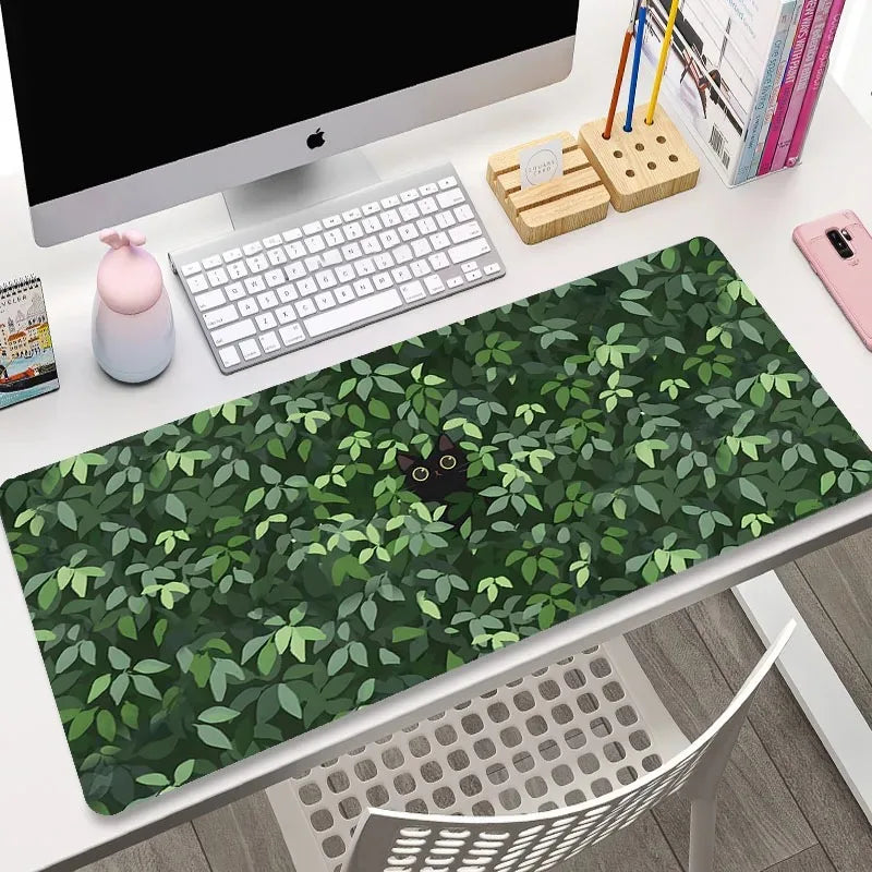 Kawaii green leaf-patterned desk mat on a desk with computer equipment.