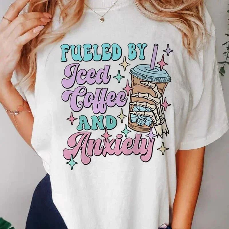 White t-shirt with colorful text and kawaii graphic of an iced coffee cup, worn by a person.