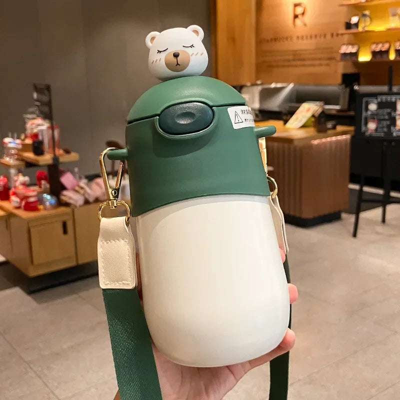 Green and white insulated kawaii mug with bear lid held in a hand, indoor setting