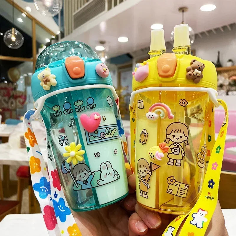 Two colorful children's kawaii water bottles with cartoon designs held in a hand.