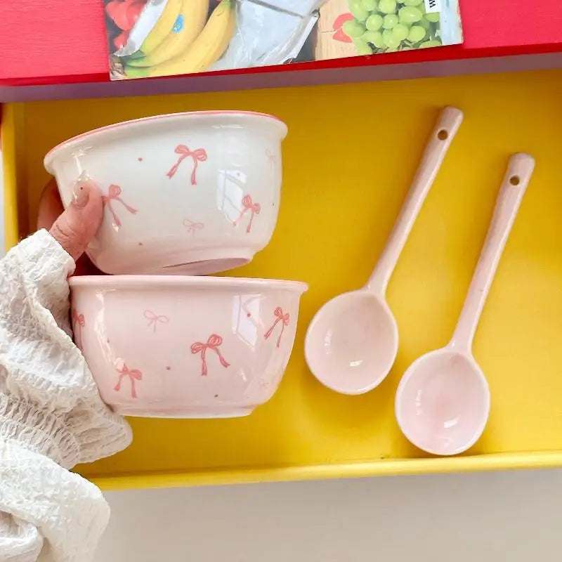 A woman holding a white bowl and a pink bowl with bows on them.