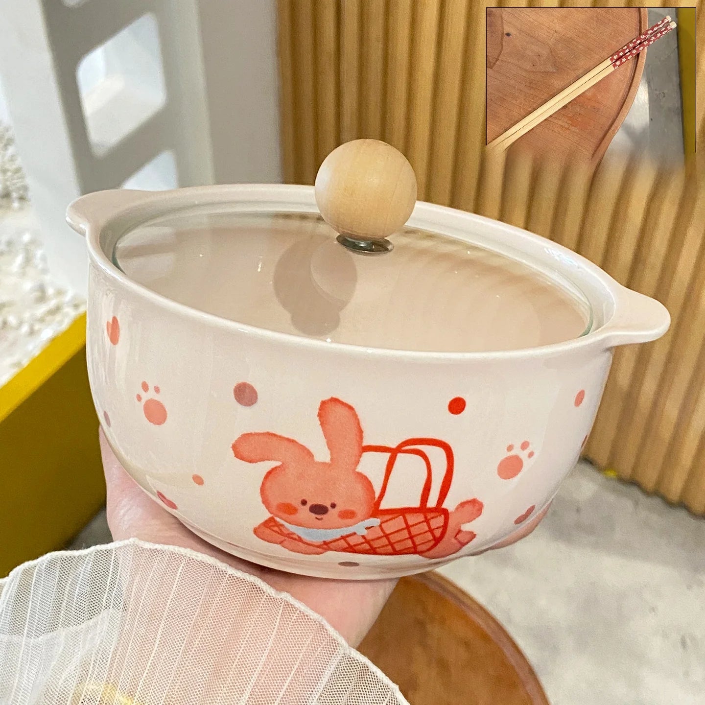 Ceramic kawaii ramen bowls with cartoon design held by a hand, wooden background