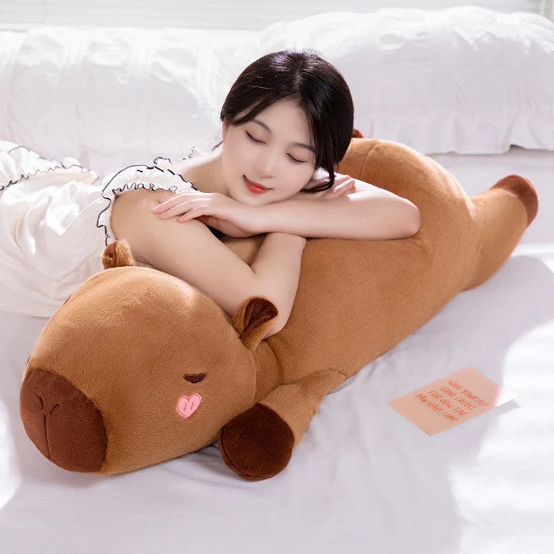 Woman lying on a large brown kawaii plush dog toy on a bed