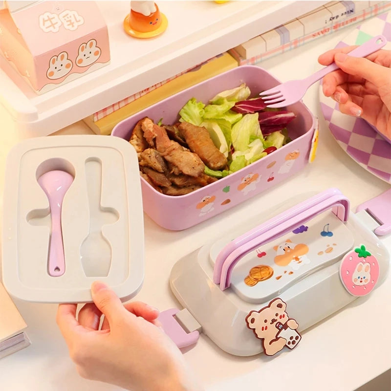 Children's kawaii lunch box set with pink spoon and fork, cartoon character design, and food inside.