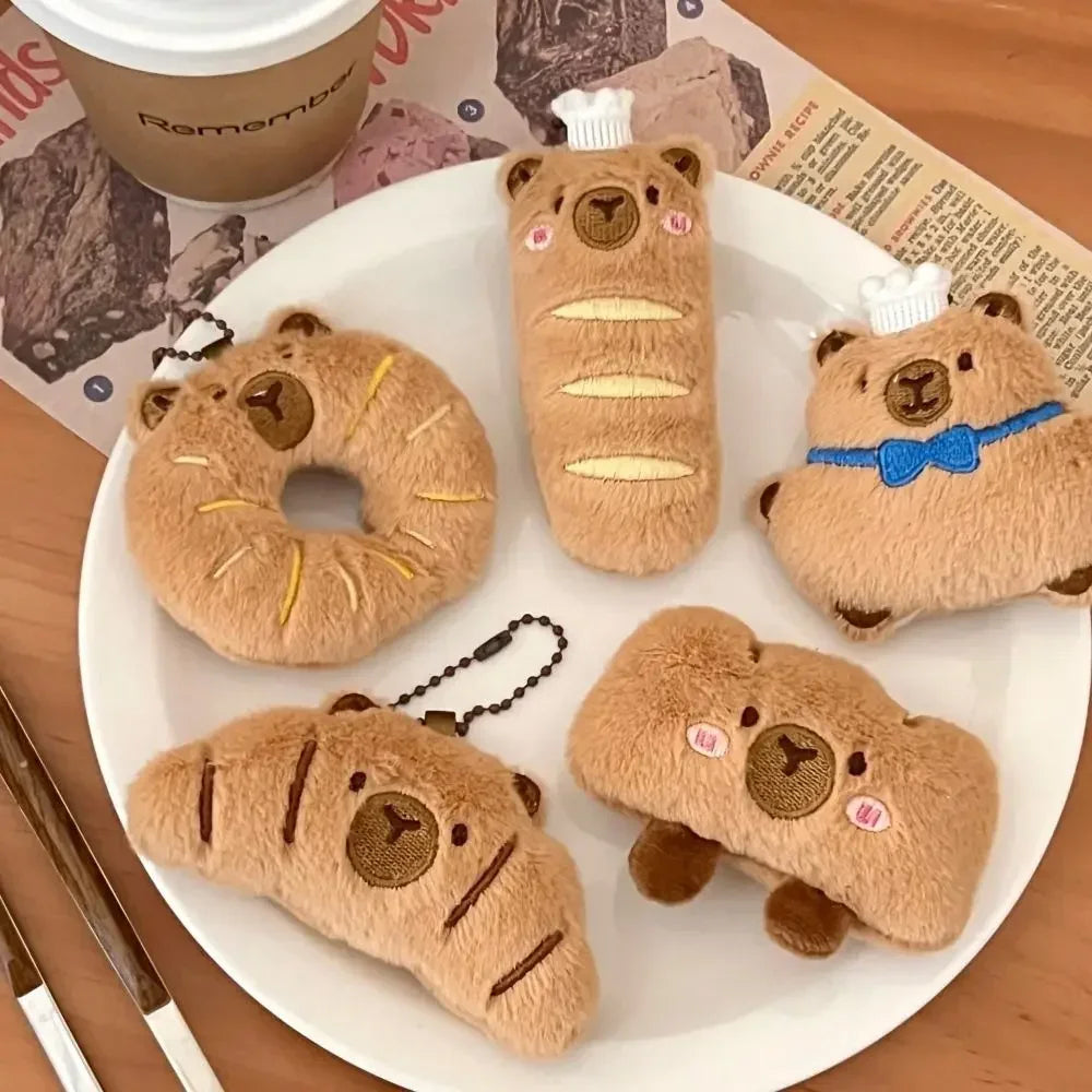 Plush kawaii toys shaped like bagels with bear faces on a white plate, with a coffee cup and newspaper in the background.