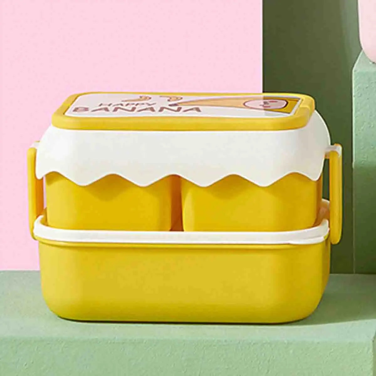 Yellow kawaii bento box with a banana design on a pink and green background
