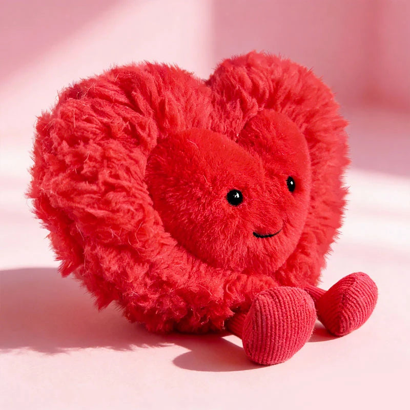 Red kawaii plush heart-shaped toy with a smiling face on a pink background