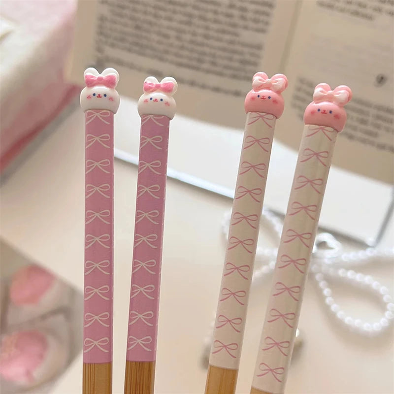 Four pink kawaii chopsticks with bow designs on a light background