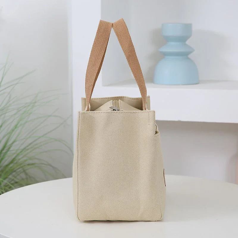 Beige kawaii tote bag with brown handles on a white surface with a light blue candle in the background.