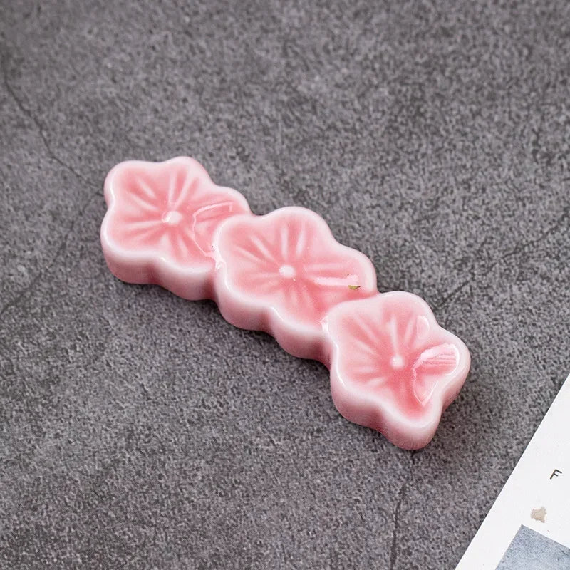 Pink flower-shaped kawaii chopstick holder on a gray surface