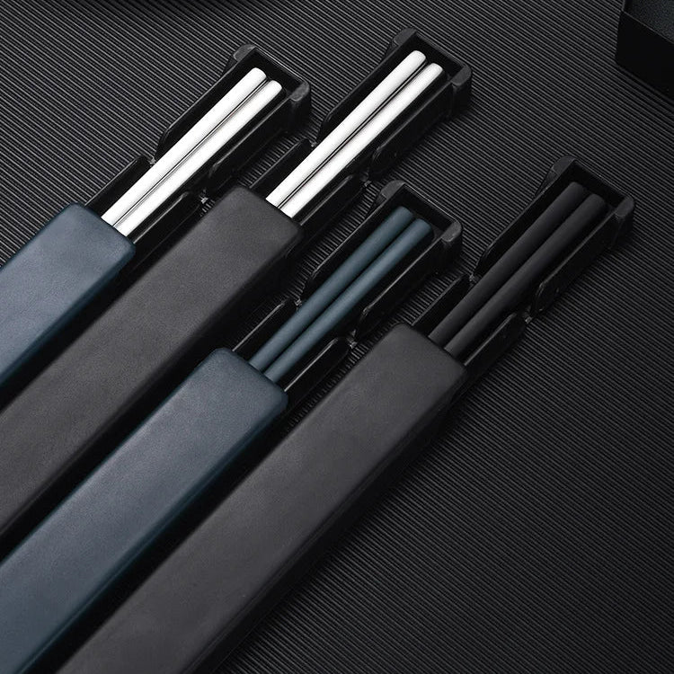 Set of black kawaii chopsticks with silver tips in a black case on a dark textured surface.