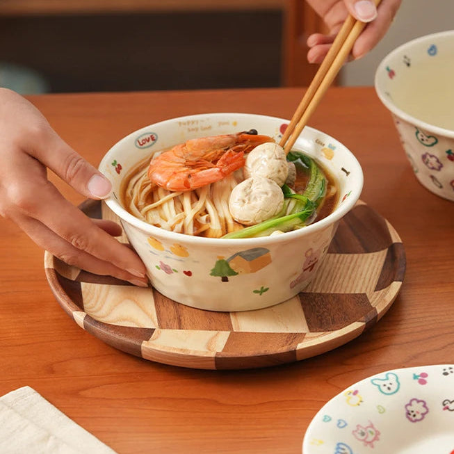 Person holding a kawaii ramen bowl of noodles with chopsticks on a wooden table