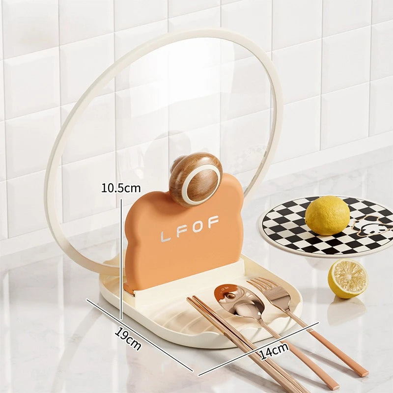 Table setting with kawaii-style cutlery holder, spoon, fork, and lemon on a white surface.