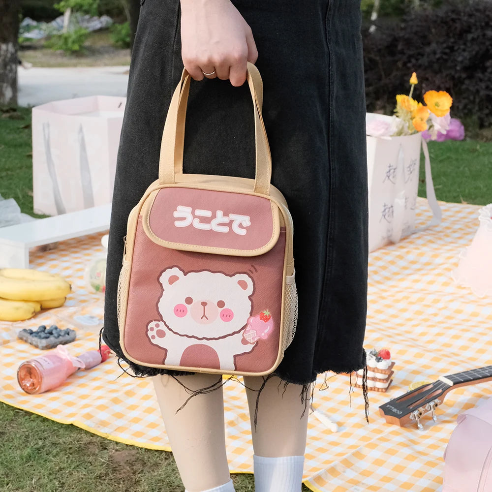 Person holding a pink kawaii bag with a bear design at an outdoor picnic.