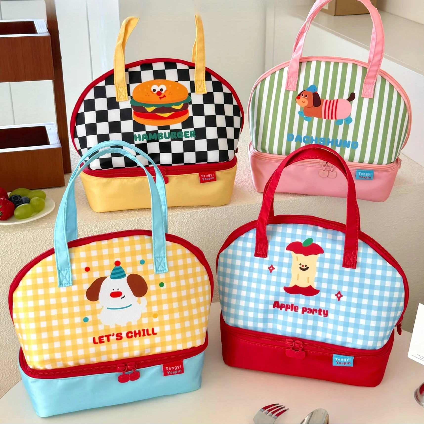 Four colorful lunch kawaii bags with cartoon designs on a kitchen counter.