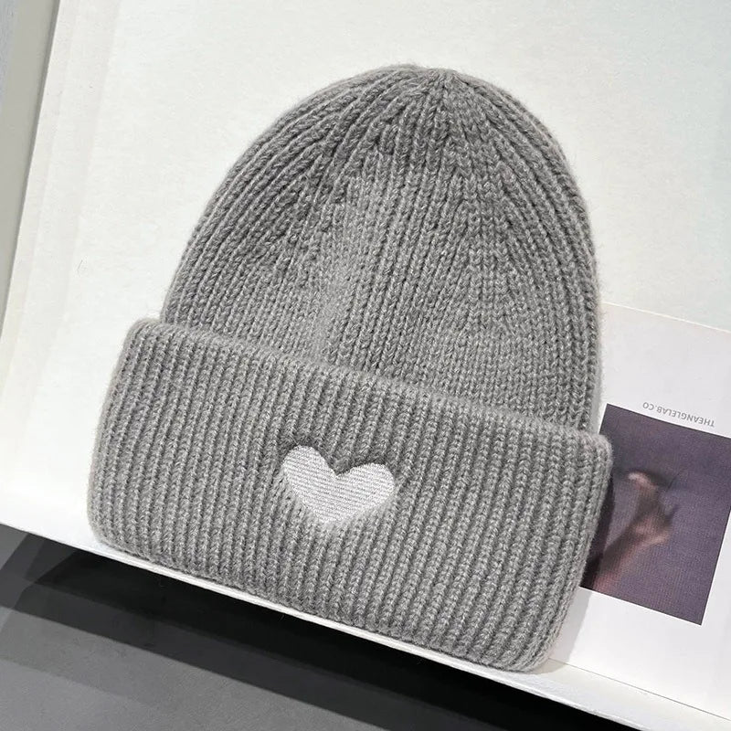 Gray knit Kawaii beanie with a heart design on a white surface