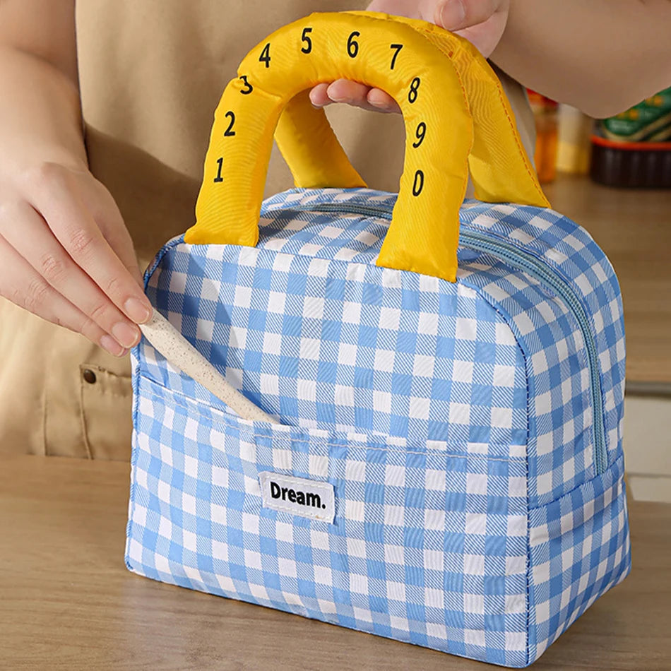 Blue and white checkered kawaii lunch bag with yellow handle featuring numbers, held by a person.