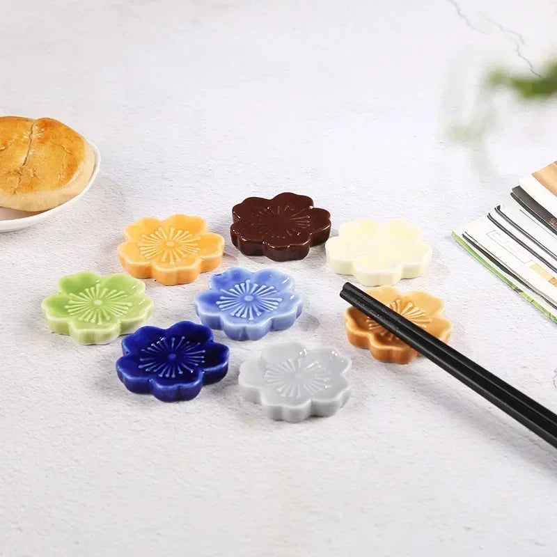 Colorful flower-shaped kawaii chopstick holders on a white surface with chopsticks.