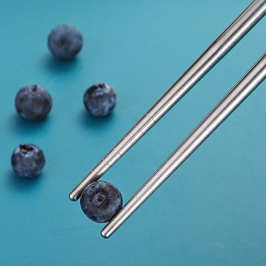 Metallic straws from a kawaii utensils set with blueberries on a teal background