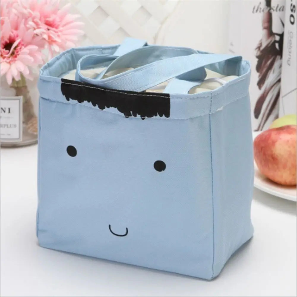 Blue kawaii lunch bag with a face design on a white surface
