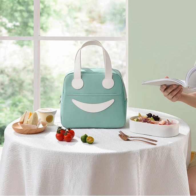 Cute smiley face kawaii lunch bag on a table with a person holding a book.