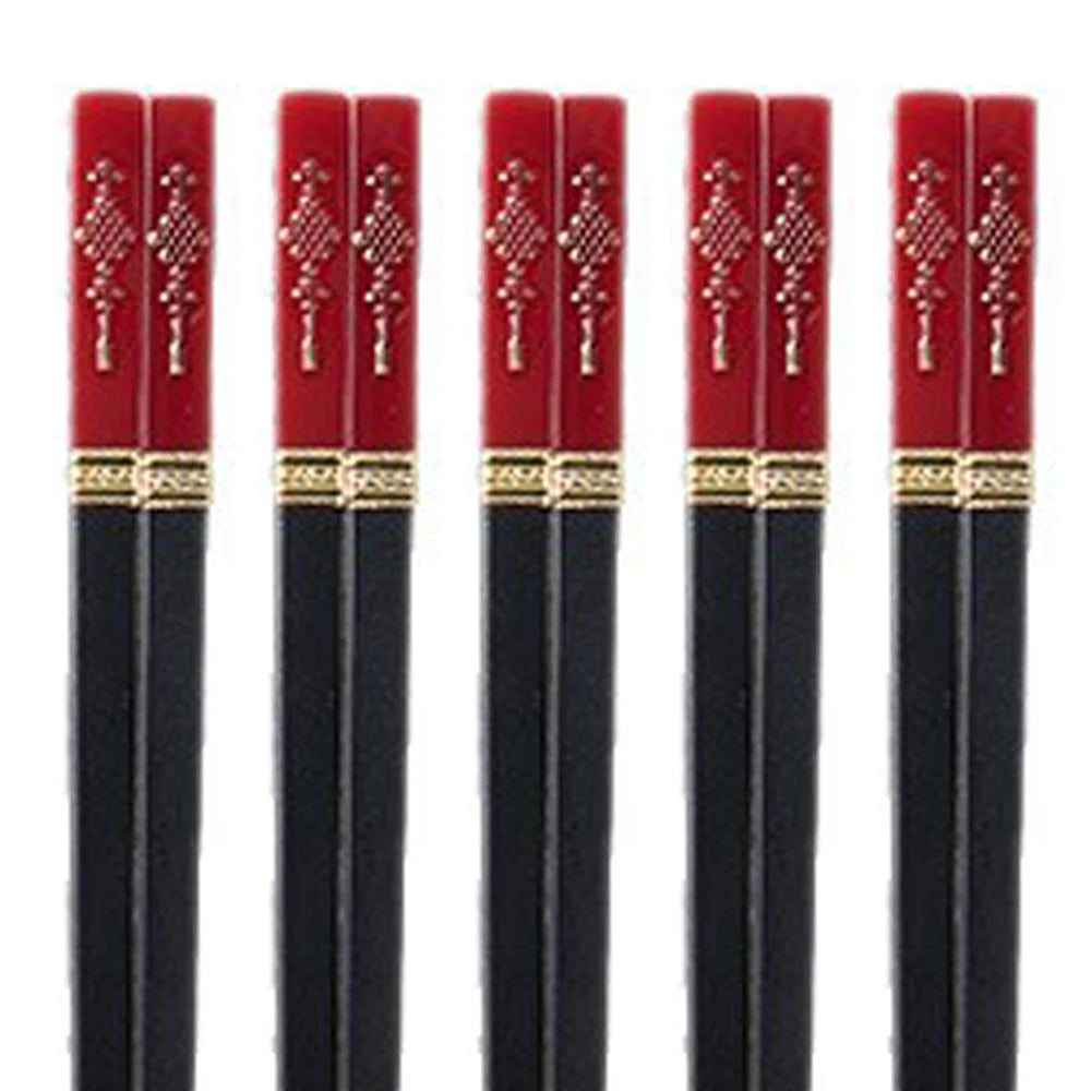 Set of black kawaii chopsticks with red and gold handles on a white background