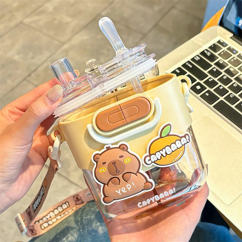 Kawaii water bottle with bear design and 'Capybara' branding held by a hand, laptop in background