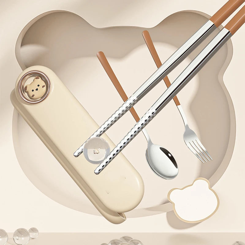Set of kawaii utensils including chopsticks, spoon, and fork on a heart-shaped background with a small bear figurine.