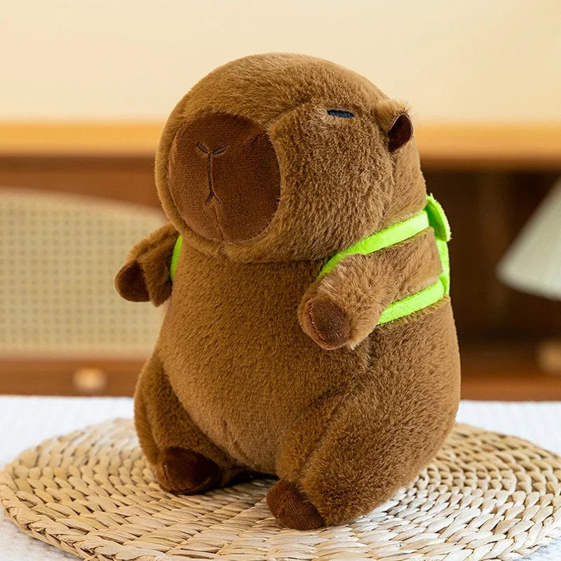 Brown kawaii plush toy with a green strap on a woven mat