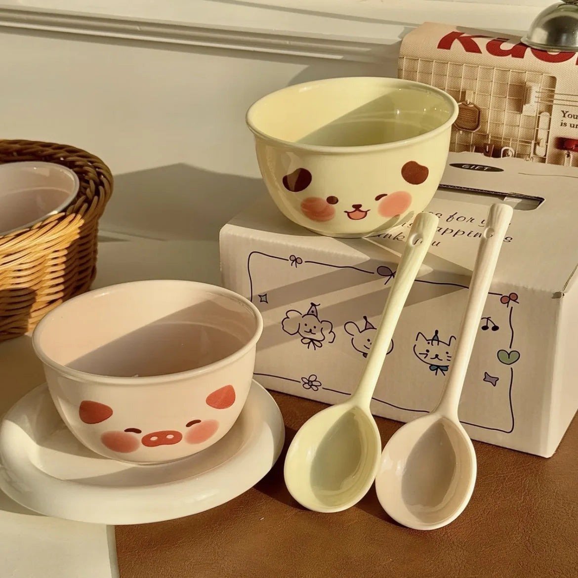 Ceramic kawaii ramen bowls and spoons with cartoon faces on a wooden surface.
