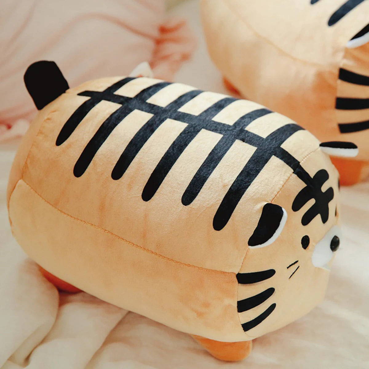 Kawaii plush tiger toy with black stripes on a soft surface
